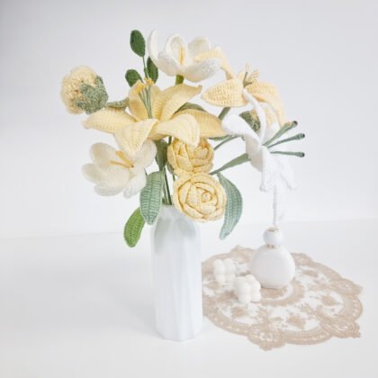 bouquet de lys au crochet jaune et blanc avec fleurs rondes crème et feuillage vert dans un vase blanc